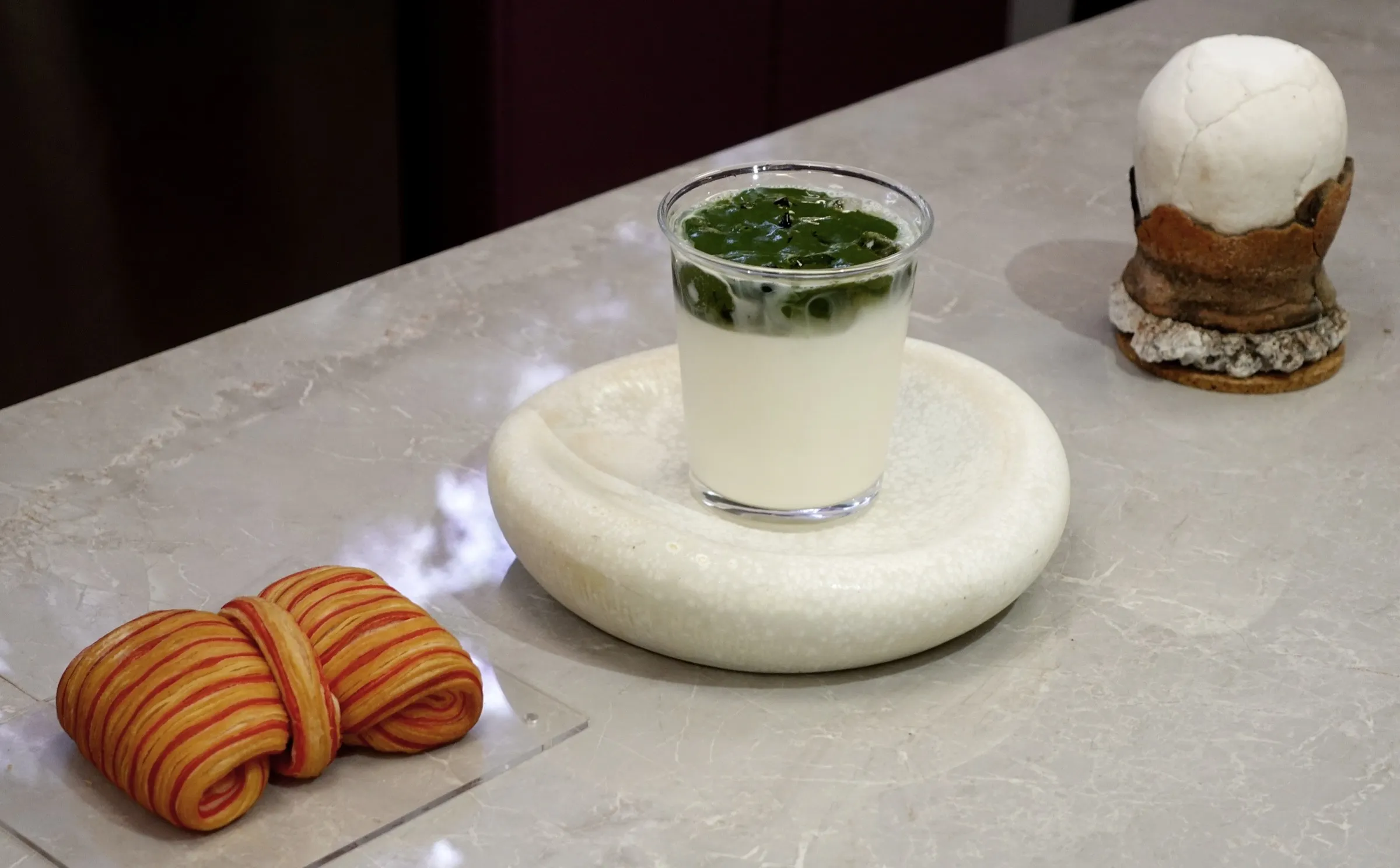 Iced matcha and a striped croissant on the café counter