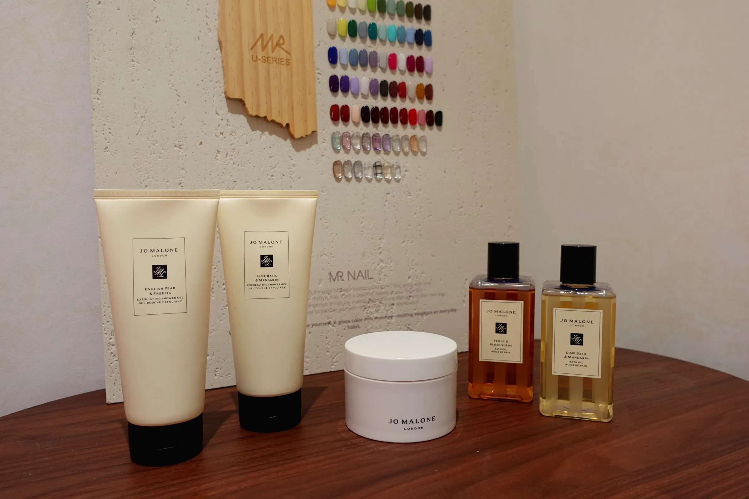 Hand and body care products on a walnut table in the Lavande spa corner, with a wall of polish swatches behind