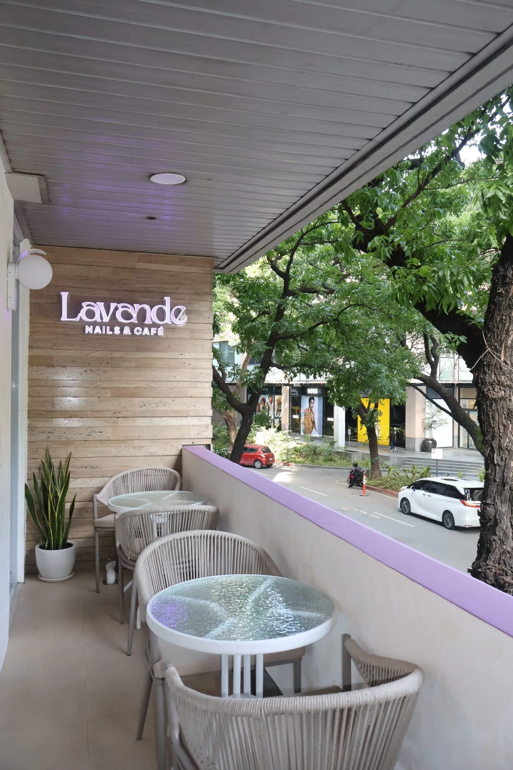 The terrace at Lavande Nails & Café, with the Lavande sign and tables looking over a tree-lined Legazpi Village street
