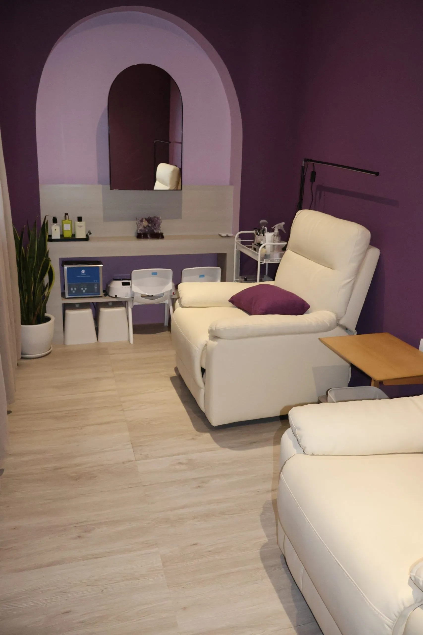 The VIP nail room at Lavande, with aubergine walls, an arched niche and cream recliners